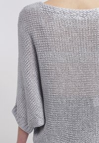 Hellgrauer, locker gestrickter Pullover mit weitem Boot-Ausschnitt und halblangen Ärmeln. Verfügt über ein strukturiertes, luftiges Muster im gesamten Design.