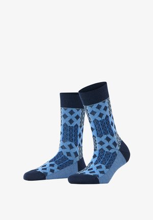 Par de calcetines hasta la mitad de la pantorrilla con patrones geométricos de diamantes y rayas en tonos de azul y azul marino sobre fondo blanco.