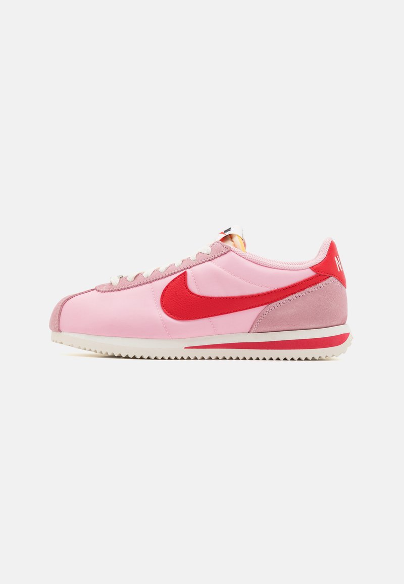 Roze i crvene Nike tenisice s glatkim tekstilnim gornjištem, nubuk detaljima, bijelim potplatom i dizajnom zupčastog potplate.