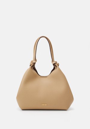 Jasno brązowa skórzana torebka o miękkim, zaokrąglonym kształcie. Posiada węzłowe paski i subtelne przeszycia. Złote logo na dole. Gładka textura.