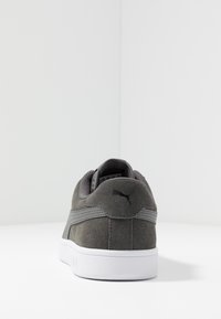 Sneaker in suede grigio con suola in gomma bianca, collarino imbottito e logo sul retro. Il design include dettagli testurizzati e cuciture.