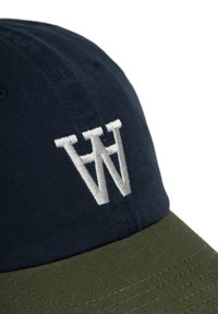 Navy színű korona és olajzöld karimájú sapka. Emelt fehér hímzett "W" logóval rendelkezik. A felülete sima, anyaga pamut.