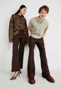 Leopard print sweater, light green polo, brown striped flared pants, leopard print high heels, brown shoes with fringe detailing.