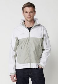 Veste légère et imperméable avec une section supérieure blanche et une section inférieure gris clair, dotée de poches zippées et d'un col montant.