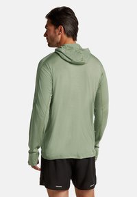 Maglietta a maniche lunghe verde chiaro con cappuccio, dall'aspetto texture, dotata di tasca a marsupio e cuciture piatte per garantire comfort.