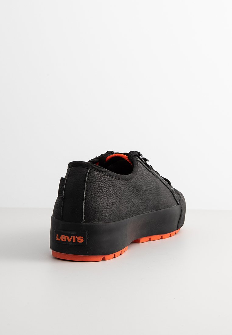 Sneaker nera con upper in pelle texturizzata, dettagli arancioni e suola in gomma. Presenta un design con lacci e il logo Levi's in evidenza sul tallone.