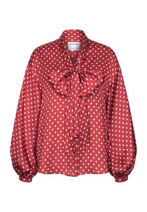 Blusa rossa a maniche lunghe con pois bianchi, caratterizzata da un grande fiocco al collo e davanti con bottoni.