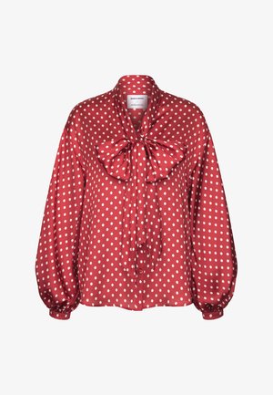Blusa rossa a maniche lunghe con pois bianchi, caratterizzata da un grande fiocco al collo e davanti con bottoni.