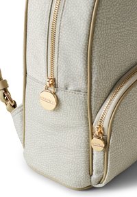 Hellgrauer Rucksack mit strukturierter Oberfläche, goldenen Reißverschlüssen und Zubehör, abgerundeten Ecken und einem kleinen Markensymbol an der Seite.