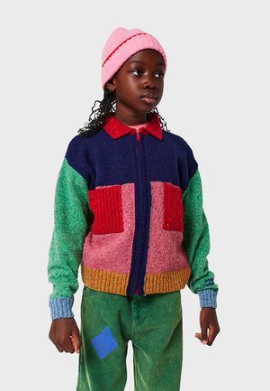 Mehrfarbige Strickjacke mit Reißverschluss; verfügt über Abschnitte in Marineblau, Grün, Rot und Pink, gerippte Taschen und kontrastierende Ärmel.