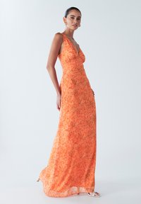 Maxi šaty v jasně oranžové barvě s květinovým vzorem, s hlubokým výstřihem do V, nastavitelnými ramínky a splývavým střihem. Hladký tkaninový povrch.