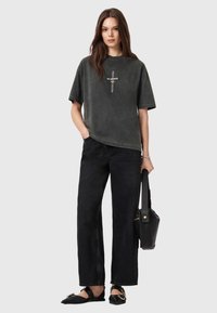 Kølig, charcoal-grå oversized t-shirt med frontprint, kombineret med sorte brede bukser og sorte flade sko. Afslappet look med en håndtaske.