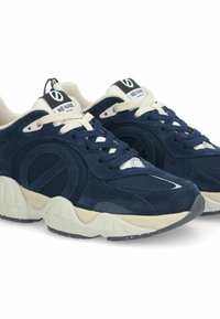 Sneakers blu navy con tomaia in suede e mesh con accenti crema, suola spessa con motivo testurizzato e etichetta con marchio sulla linguetta.