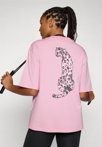Tricou roz cu o croială lejeră, având un grafic cu imprimeu de leopard negru și gri pe spate. Fabricat din material moale din bumbac.