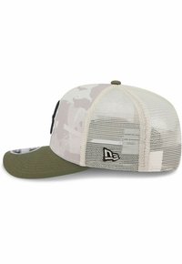 Trucker-Cap mit grünem Stoffvisier, weißem Mesh-Rücken und grauem Camouflage-Muster auf der Vorderseite. Schwarzes Logo-Highlight an der Seite.