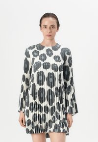Faltenkleid in Schwarz und Weiß mit Blumenmuster, mit langen Ärmeln und rundem Ausschnitt, aus einem glatten Stoff gefertigt.