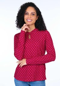 Langärmliges Oberteil in Magenta mit rosa Punkten, das einen Schlitz-Ausschnitt am Hals bietet und eine lockere Passform hat. Weiche, glatte Textur.