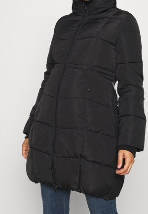 Czarna pikowana kurtka puchowa z przednim zamkiem błyskawicznym, wysokim kołnierzem, bocznymi kieszeniami na zamek, noszona przez osobę w niebieskich dżinsach.