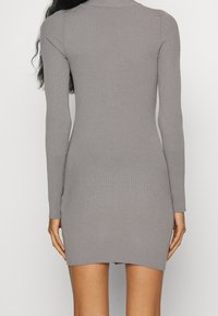 Robe à manches longues côtelée de couleur grise, style ajusté, avec un col montant et un ourlet au-dessus du milieu de la cuisse. Texture douce, design minimaliste.