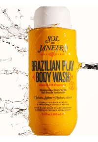 Jasnożółta butelka Sol de Janeiro Brazilian Play Body Wash z wodą rozpryskującą się wokół niej na białym tle.