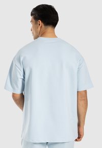 Maglietta a maniche corte azzurro chiaro, vestibilità morbida, texture soffice, design semplice, scollo rotondo, presenta orlo cucito e spalle abbassate.