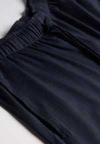 Navyblauwe elastische tailleband broek met een gladde textuur en een losse pasvorm, voorzien van zijzakken en subtiele drapering in de stof.
