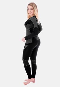Black athletic long-sleeve top with gray accents and fitted black leggings, featuring a textured design and contrasting panel details.