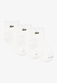 Λευκές κάλτσες αστραγάλου, υφή πλεκτού με ραβδώσεις, με οδοντωτή μανσέτα, διακοσμημένες με πράσινο κεντημένο λογότυπο κροκοδείλου. Πακέτο με τρία ζεύγη.