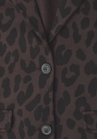 Brun blazer med sorte leopardpletter, to forreste knapper og to klaplommer, der viser den øverste forreste del.