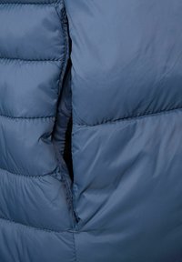 Blått puffjacka med kviltat mönster, med horisontell sömdesign, mjuk textur och sidoficköppning.