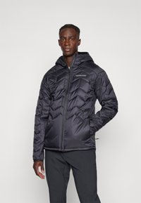 Schwarze Daunenjacke mit Kapuze, ausgestattet mit einem Zickzack-Steppdesign, Reißverschluss und dem Peak Performance-Logo auf der Brust.