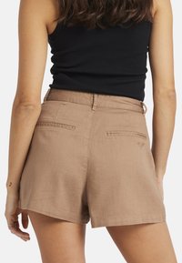 Ruske linne shortsit, joissa on struktuurinen pinta, kahdella takataskulla ja pienellä brodeeratulla yksityiskohdalla. Leikkaukseltaan rento malli.