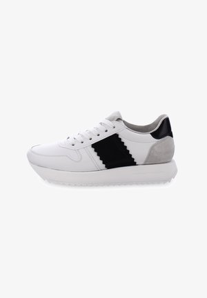White leather sneakers featuring a black zigzag accent, gray suede heel, and textured outsole. Designed with flat laces and rounded toe.
