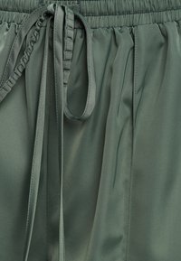 Satijnen shorts in een gedempte groene kleur, voorzien van een elastische tailleband met een trekkoord en een zachte, gladde textuur.