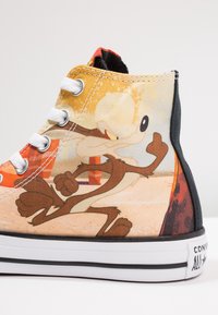 Kanvasové tenisky s vysokým střihem, které prezentují barevný design s kreslenou postavičkou. Hlavními barvami jsou oranžová a žlutá. Bílé očky a černá podrážka.