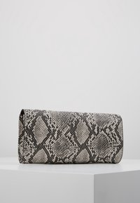 Obdélníková kabelka s hadím vzorem v černé a šedé barvě. Vyrobena z texturovaného materiálu, má klopu a měkké hrany.