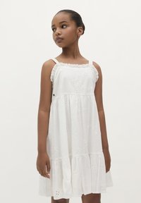Weißes Baumwollkleid mit floralem Stickereimuster, Rüschenträgern und gestuften Saum. Leichter Stoff mit lockerer Passform, ideal für warmes Wetter.
