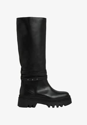Sorte læder knæhøje støvler med flad, chunky sål og dekorative krydsremme med små sølvnitter. Glat tekstur med et elegant design.