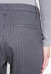 Grijze gestreepte broek met een achterzak. Het materiaal lijkt textuur te hebben met fijne lijnen en een tailored ontwerp.