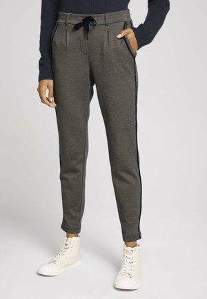 Pantalons de jogging à carreaux en gris et noir. Dotés de bandes latérales, d'une taille élastique avec cordon de serrage et de poches avant. Portés avec des baskets montantes beiges.