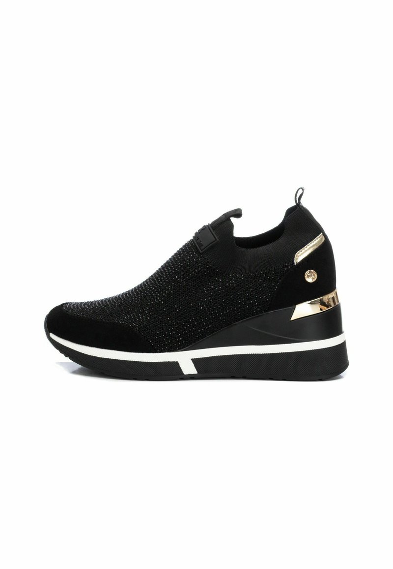 Chaussure de sport noire avec une tige en tricot texturé, un talon compensé et un accent doré sur le talon. Semelle en caoutchouc avec des détails en bande blanche.