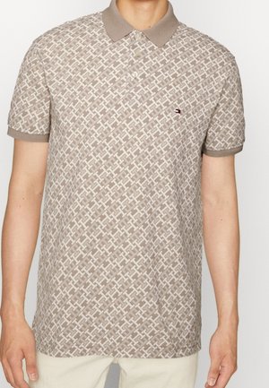 Polo beige con motivo geometrico, maniche corte e colletto a contrasto. Presenta un piccolo logo sul petto. Materiale in cotone.