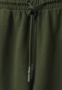 Olijfgroene sweatpants met een elastische tailleband en een gevlochten trekkoord met plastic uiteinden, gemaakt van een zachte, gestructureerde stof.