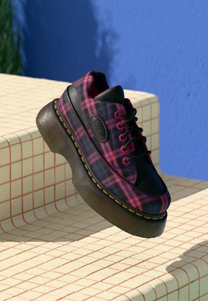 Sneakers platform a scacchi neri e rosa con punta tonda, suola in gomma rialzata, dettagli in pelle nera e cuciture gialle a contrasto.