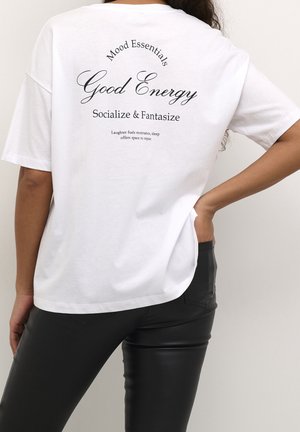 Biała koszulka z bawełny z czarnym nadrukiem na plecach, z frazami takimi jak "Dobra energia" i "Nieodzowne elementy nastroju" w różnych czcionkach.