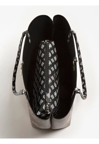 Czarna i srebrna torba na ramię o fakturowanym wykończeniu. Wnętrze wyposażone jest w kontrastową czarną podszewkę z białymi geometrycznymi wzorami oraz kieszeń na zamek.