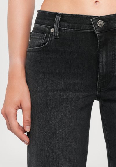 Black denim jeans with a slim fit. Features a front pocket, silver button closure, and a textured finish for a sleek appearance.