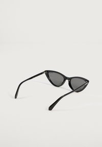 Čierne slnečné okuliare typu cat-eye značky Polaroid s tmavými polarizovanými sklami na bielom pozadí.