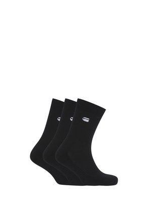 Trois paires de chaussettes noires montantes avec un petit logo blanc sur le dessus, disposées côte à côte sur un fond blanc.