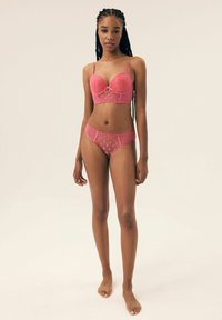 Różowy koronkowy zestaw bielizny z haftem, zawierający usztywniany stanik z kwiatowymi wzorami oraz pasujące majtki o wysokim stanie, z półprzezroczystymi wstawkami z siateczki.